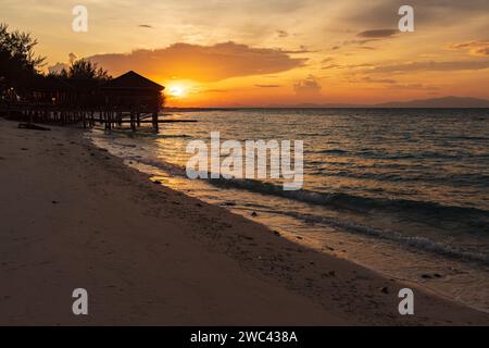 Sunrise silhouettes un quai et un belvédère sur une belle plage tropicale Banque D'Images