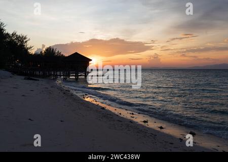 Sunrise silhouettes un quai et un belvédère sur une belle plage tropicale Banque D'Images