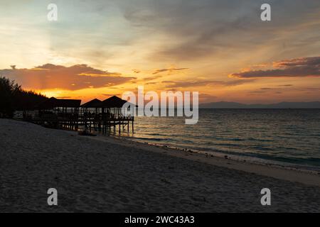 Sunrise silhouettes un quai et un belvédère sur une belle plage tropicale Banque D'Images