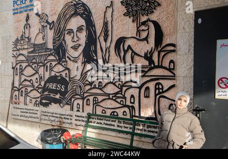 Amman, Amman, Jordanie. 13 janvier 2024. Une femme palestinienne assise à l'entrée de l'hôpital de Jénine à côté de la fresque en l'honneur de Shireen Abu Akleh, une journaliste américano-palestinienne de premier plan qui a travaillé comme journaliste pendant 25 ans pour Al Jazeera, avant d'être tuée par un soldat israélien. (Image de crédit : © Bruno Gallardo/ZUMA Press Wire) USAGE ÉDITORIAL SEULEMENT! Non destiné à UN USAGE commercial ! Banque D'Images