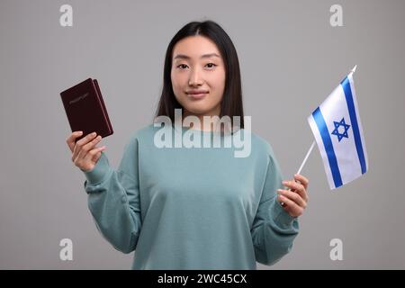 Immigration en Israël. Femme avec passeport et drapeau sur fond gris Banque D'Images