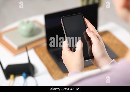 Femme avec smartphone se connectant à Internet via routeur Wi-Fi à l'intérieur, gros plan Banque D'Images