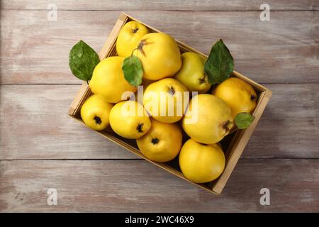 Savoureux fruits de coing mûrs dans la caisse sur la table en bois, vue de dessus Banque D'Images