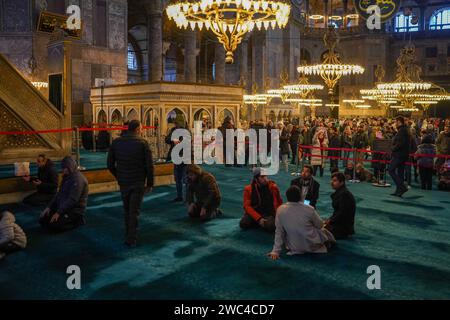 Istanbul, Turquie. 13 janvier 2024. Les musulmans offrent leurs prières dans la section à gauche, tandis que les touristes visitent le musée à droite. La Sainte-Sophie, a été transformée de musée en mosquée en 2020 par décision du président Erdogan, les visiteurs qui sont des touristes seront facturés une taxe de 25 euros à partir du 15 janvier 2024, par décision du ministère de la Culture et du Tourisme. Crédit : SOPA Images Limited/Alamy Live News Banque D'Images