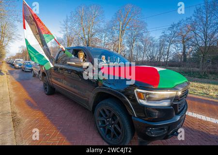 Un partisan pro-palestinien agite des drapeaux en passant devant le Palais de la paix pendant l'audience de la Cour internationale de Justice (CIJ). L’Afrique du Sud a présenté ses arguments contre l’État d’Israël lors de sa session de trois heures à la Cour internationale de Justice (CIJ) à la Haye. Le plan d'Israël pour "détruire" Gaza vient du "plus haut niveau de l'Etat", a entendu la haute cour de l'ONU. L ' Afrique du Sud a également demandé à la CIJ d ' ordonner à Israël de cesser immédiatement toute action militaire. Des avocats sud-africains ont accusé Israël pf de génocide. Israël, aura son jour à la (CIJ) pour définancer sa défense vendredi - h Banque D'Images