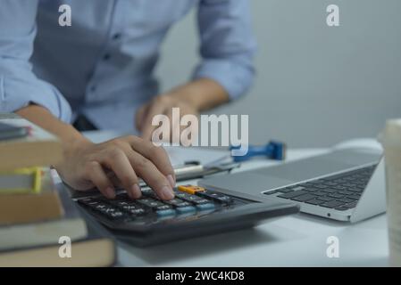 Homme d'affaires utilisant la calculatrice et les documents comptables au bureau avec ordinateur portable. Banque D'Images