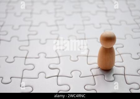 Une poupée en bois sur puzzle blanc. Concept de solitude. Banque D'Images