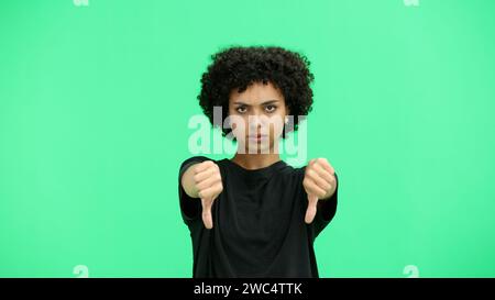 Une femme, gros plan, sur fond vert, montre ses pouces vers le bas Banque D'Images
