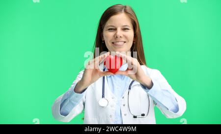 Femme médecin, gros plan, sur un fond vert, montre un cœur Banque D'Images