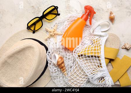 Sac à ficelle avec lunettes de soleil, bouteille de crème solaire et accessoires de plage sur fond de gringe léger Banque D'Images