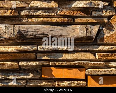 Les murs de maçonnerie sont faits de pierre plate sauvage grise mélangée avec des briques et une barre en bois. Côté lumière naturelle du soleil. Espace de copie. Gros plan. Banque D'Images