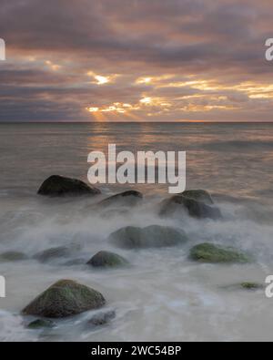 Une vue panoramique sur une plage rocheuse contre la mer au coucher du soleil Banque D'Images