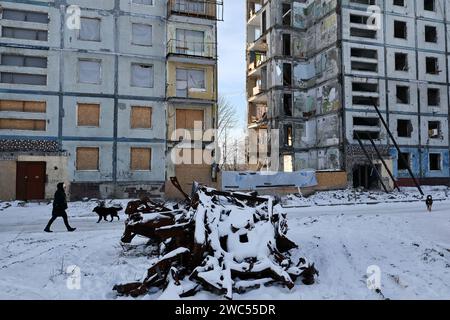 Zaporizhzhia, Ukraine. 13 janvier 2024. Une femme et des chiens errants sont vus sur la route près de l'immeuble qui a été lourdement endommagé par les bombardements russes à Zaporizhzhia. Le président ukrainien Volodymyr Zelenskiy a déclaré qu’il était plus convaincu aujourd’hui que le mois dernier que son pays obtiendrait une nouvelle aide financière des États-Unis. Mais rien n’indiquait à Washington que l’approbation par le Congrès d’un paquet d’aide proposé par la Maison Blanche serait bientôt disponible. Crédit : SOPA Images Limited/Alamy Live News Banque D'Images