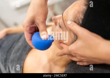 Client recevant des ventouses faciales dans un salon de beauté Banque D'Images