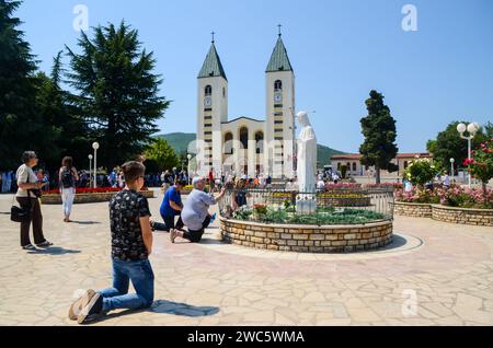 Međugorje, Bosnie-Herzégovine. Pèlerins catholiques priant à Medjugorje. Les gens qui assistent à une sainte messe. Église et statue de la Vierge Marie Banque D'Images