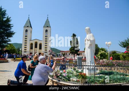 Međugorje, Bosnie-Herzégovine. Pèlerins catholiques priant à Medjugorje. Les gens qui assistent à une sainte messe. Église et statue de la Vierge Marie Banque D'Images