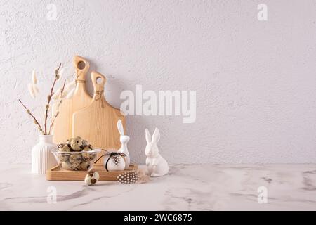 Comptoir en pierre de cuisine décoré pour Pâques dans des couleurs claires. figurines en céramique de lapin, un vase avec des brindilles de saule, un bol avec des œufs de caille. Banque D'Images