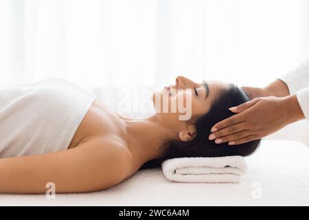 Femme calme se livrant à un massage de la tête soulageant le stress Banque D'Images