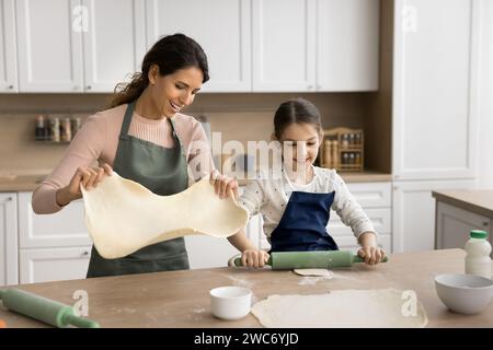 Heureuse fille d'enfant aidant maman à cuire, préparant des tartes maison Banque D'Images