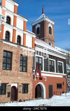 La vue hivernale des vieilles maisons de ville historiques de Kaunas avec des drapeaux et la tour basilique cathédrale dans un arrière-plan (Lituanie). Banque D'Images