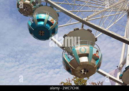 Gondoles et rayons d'une grande roue lors d'un festival de la ville à Marburg, Allemagne en octobre 2023 contre un ciel bleu et blanc. Banque D'Images