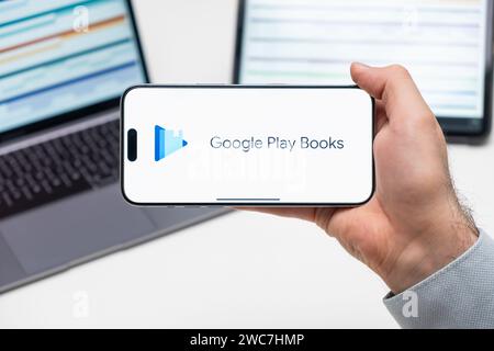 Google Play Books logo de l'application sur l'écran du téléphone portable tenu par l'homme devant l'ordinateur portable et la tablette, décembre 2023, Prague, République tchèque Banque D'Images