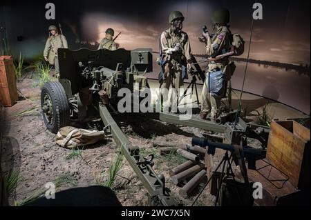 quatre soldats parlent. Détail d'un bataillon de soldats aéroportés américains derrière un canon antichar léger QF de 6 livres modèle M1 57mm la nuit. Banque D'Images