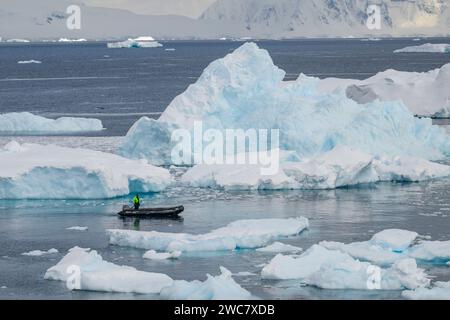 Zodiac naviguant à travers les eaux glacées de Neko, port, Antarctique, vue rapprochée des icebergs au sol se reflétant sur les eaux environnantes Banque D'Images