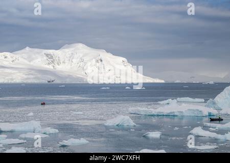 Zodiac naviguant à travers les eaux glacées de Neko, port, Antarctique, vue rapprochée des icebergs au sol se reflétant sur les eaux environnantes Banque D'Images