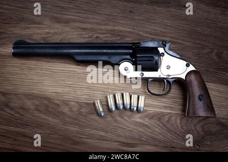 Revolver à action simple de calibre Old West .44 avec des ronds sur fond en bois Banque D'Images