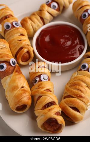 Assiette avec de savoureuses momies de saucisse pour la fête d'Halloween et ketchup sur la table, gros plan Banque D'Images