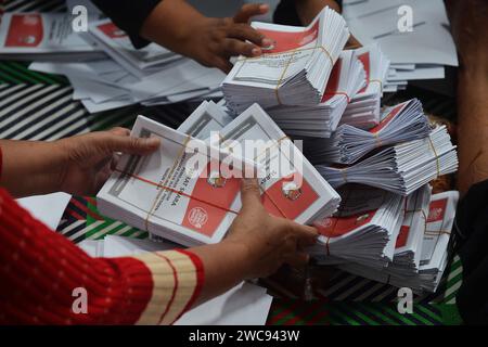 Magelang, Java central, Indonésie. 11 janvier 2024. Un travailleur plie des bulletins de vote et montre des photos de candidats à la présidence sur des bulletins de vote pour l'élection présidentielle du 14 février montrant les candidats, de gauche à droite, Anies Baswedan et son coéquipier Muhaimin Iskandar, Prabowo Subianto et son coéquipier Gibran Rakabuming Raka, et Ganjar Pranowo et son coéquipier Mahfud MD, lors des préparatifs pour la distribution de la logistique électorale à Magelang, Java central, le 11 janvier 2024. La troisième plus grande démocratie du monde a établi la liste électorale permanente (DPT) pour l'élection générale de 2024 à 20 Banque D'Images