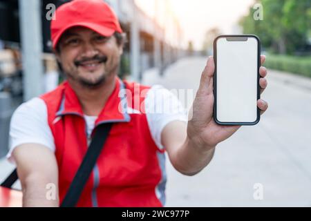 Un chauffeur de livraison de nourriture montrant l'écran du téléphone, invitant les clients à utiliser l'application mobile pour passer des commandes de nourriture. Banque D'Images