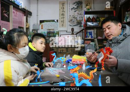 ZOUCHENG, CHINE - 14 JANVIER 2024 - Sun Yandou, artiste de figurine de pâte folklorique, guide les enfants pour réaliser une série de dragons de figurine de pâte dans la ville de Zoucheng, Shan Banque D'Images