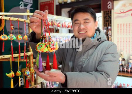 ZOUCHENG, CHINE - 14 JANVIER 2024 - Sun Yandou, artiste de sculpture de pâte folklorique, montre un pendentif dragon de sculpture de pâte dans la ville de Zoucheng, province du Shandong Banque D'Images