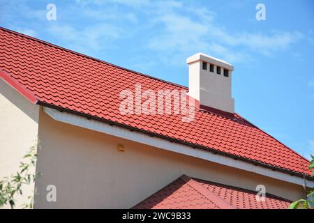 Toit en tuile métallique rouge. Maison en métal couleur rouge toit avec cheminée. Banque D'Images