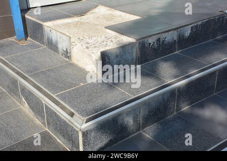 carrelage cassé à l'extérieur des escaliers de porche, les marches de la maison ont besoin de rénovation, réparation des carreaux cassés lâches. Banque D'Images