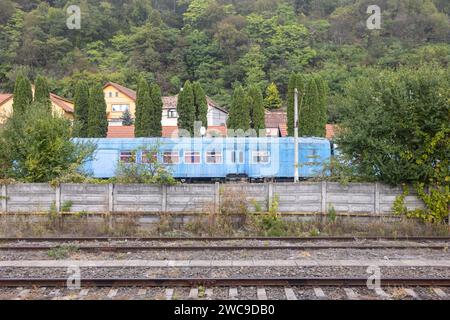 Un train bleu stationné dans un quartier résidentiel, le long d'un ensemble de voies ferrées Banque D'Images