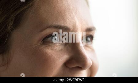 Yeux bleus d'une jeune femme d'âge moyen regardant loin Banque D'Images