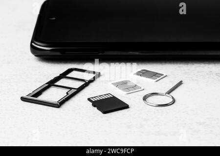 Smartphone et emplacements ouverts pour cartes nano SIM, deux cartes nano SIM, lecteur micro SD et clé métallique gros plan, photo noir et blanc Banque D'Images