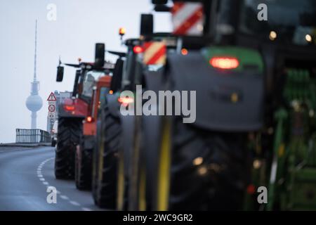 Berlin, Allemagne. 15 janvier 2024. Des tracteurs se dirigent vers le centre-ville pour une manifestation de protestation à la porte de Brandebourg. La tour de télévision peut être vue en arrière-plan. Selon la police, environ 10 000 participants et 5 000 véhicules devraient prendre part à une grande manifestation des associations d'agriculteurs et de l'association des expéditeurs BGL. Les protestations sont dirigées contre les réductions de subventions prévues par le gouvernement fédéral, y compris pour le diesel agricole. Crédit : Sebastian Christoph Gollnow/dpa/Alamy Live News Banque D'Images