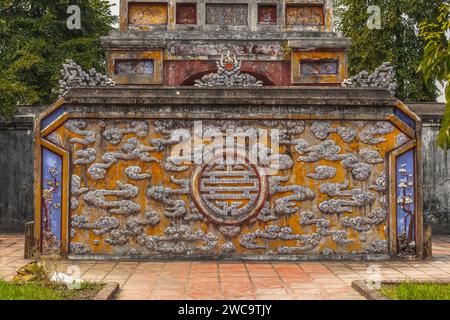 Relief orné de mur de pierre avec détail de nuage dans une ville impériale à Hué, Vietnam. Capturée par une journée ensoleillée. Traduction : porte Dien Tho Banque D'Images