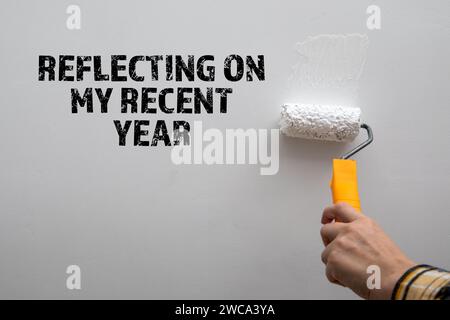 Réflexion sur ma dernière année. Peignez un mur blanc avec un rouleau à peindre. Banque D'Images