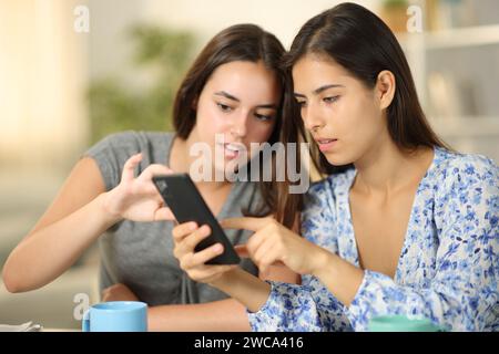 Amis parlant de contenu de téléphone à la maison Banque D'Images