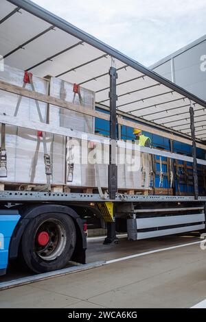 Récepteur d'entrepôt debout à l'intérieur du camion dans la zone de cargaison, remorque. Réceptionniste tenant la tablette, regardant les détails de la cargaison, vérifiant les articles livrés Banque D'Images