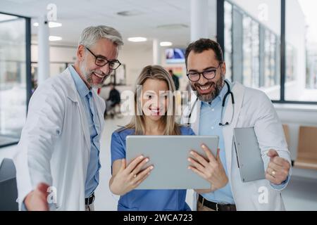 Portrait de médecins et d'infirmières debout dans le couloir hospitalier. Les travailleurs de la santé dans une clinique privée moderne, regardant la tablette, souriant. Banque D'Images