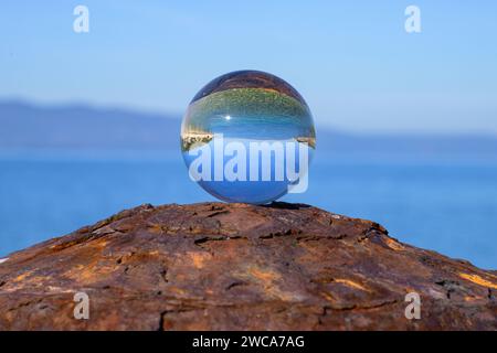 Boule de verre couchée sur une borne rouillée, journée ensoleillée en automne à Cres (Croatie), mer et ciel bleu Banque D'Images