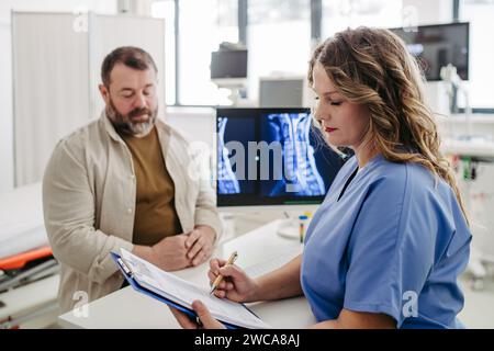 Médecin consultant le patient en surpoids, discutant du résultat du test et des scans de rayons X dans le cabinet du médecin. Notion de risques sanitaires de surwhite et d'obésité. Banque D'Images