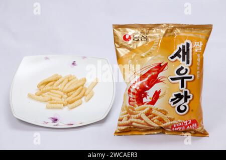 Ulsan, Corée du Sud - 14 janvier 2024 : une exposition présentant des craquelins de crevettes Saeukkang sur une assiette à côté de leur sac non ouvert, capturant l'essence de t Banque D'Images