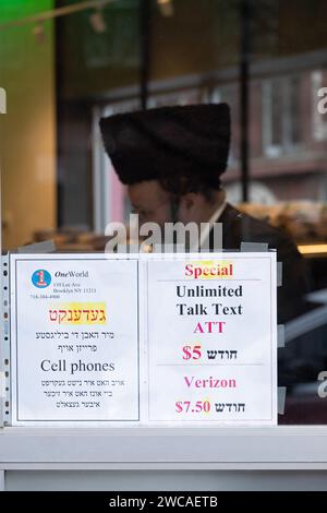 Une publicité bilingue en yiddish et en anglais pour les téléphones portables et le service avec un homme hassidique en arrière-plan. Sur Bedford Avenue à Brooklyn, New York Banque D'Images
